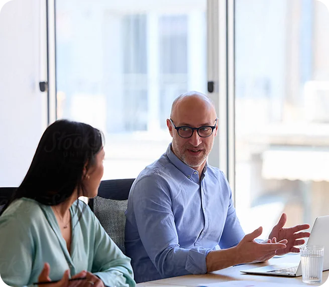 Two professionals discussing virtual care program planning and healthcare consulting strategies during a meeting with a laptop.