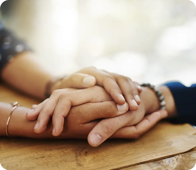 Close-up of people placing their hands together in a supportive gesture, representing teamwork and collaboration in healthcare.
